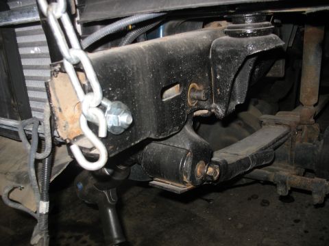 1995 Ford C-350 (Centurion Conversions) - This photo shows a close-up view of a vehicle's suspension system, focusing on a leaf spring and its mounting bracket.