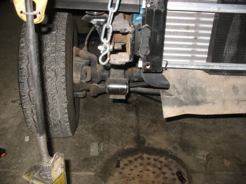 1995 Ford C-350 (Centurion Conversions) - Close-up view of the front suspension and tire of a vehicle, with a chain secured to the frame.