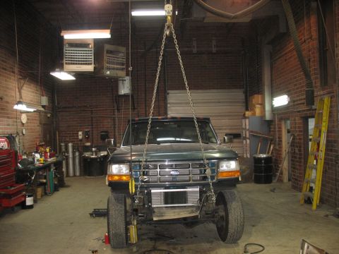 1995 Ford C-350 (Centurion Conversions) - Front view of a 1995 Ford C-350 (Centurion Conversions) being hoisted in a workshop.