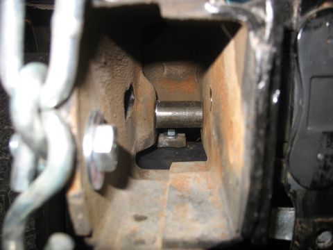 1995 Ford C-350 (Centurion Conversions) - Detail of a rusty metal suspension component, showing a bolt and chain linkage.