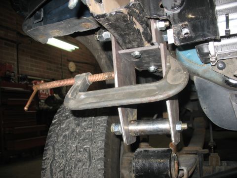 1995 Ford C-350 (Centurion Conversions) - A C-clamp is attached to a vehicle's suspension system, obscuring the exact model and year.