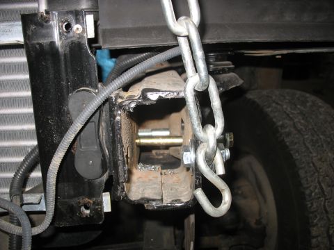 1995 Ford C-350 (Centurion Conversions) - This image shows a close-up view of a vehicle's front suspension component, possibly modified, with a heavy-duty chain secured to it.