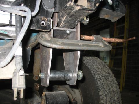 1995 Ford C-350 (Centurion Conversions) - A custom suspension component is being worked on, secured with a clamp.