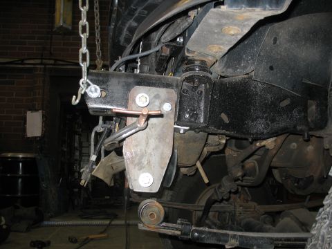 1995 Ford C-350 (Centurion Conversions) - Close-up of vehicle front suspension components, including a custom bracket and leaf spring.