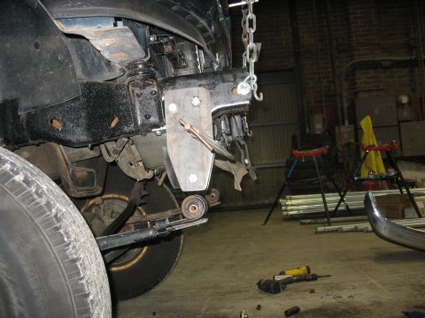 1995 Ford C-350 (Centurion Conversions) - Custom bracket being installed on vehicle frame, with tools and parts on the floor.