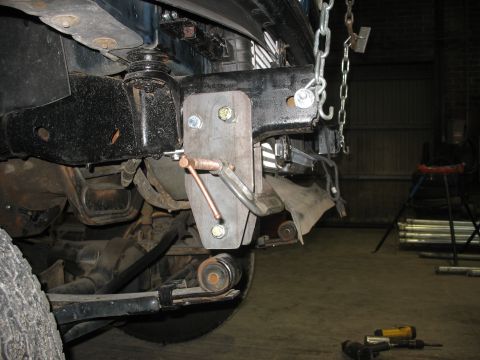 1995 Ford C-350 (Centurion Conversions) - A close-up view of a custom-fabricated bracket attached to the front frame of a vehicle.