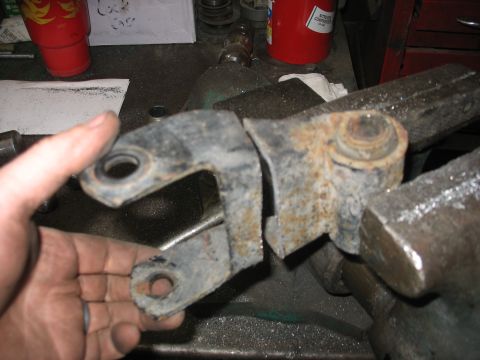 1995 Ford C-350 (Centurion Conversions) - A heavily rusted metal suspension component is clamped in a vise, showing signs of wear and damage.