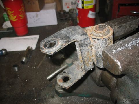 1995 Ford C-350 (Centurion Conversions) - A rusty vehicle suspension part is held securely in a vise, ready for work in a garage setting.
