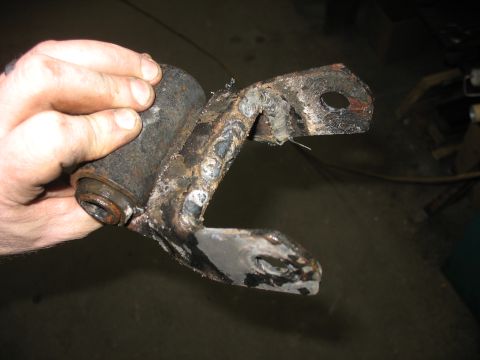 1995 Ford C-350 (Centurion Conversions) - A rusty metal suspension part, likely from a vehicle, is held by a hand.
