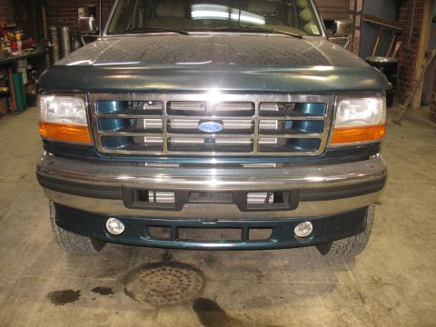 1995 Ford C-350 (Centurion Conversions) - The front grille and bumper of a dark green Ford truck are visible.