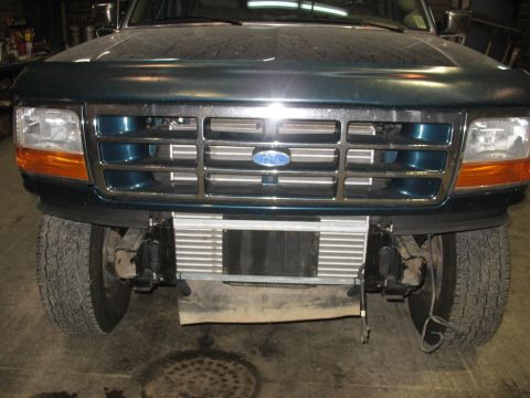 1995 Ford C-350 (Centurion Conversions) - Front view of a green Ford truck, revealing its grille, headlights, and intercooler assembly.