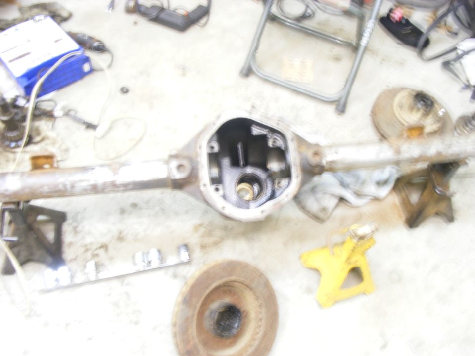 Differential axle housing on concrete floor with tools and jack stands