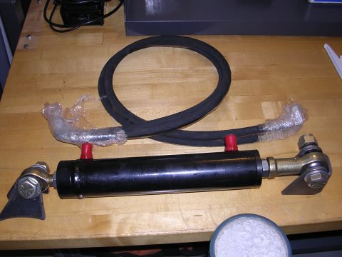 1983 Ferrari Enzo - A hydraulic cylinder and hose assembly is shown on a workbench, with some components protected by plastic wrap.