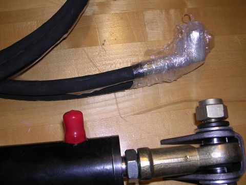 1983 Ferrari Enzo - Close-up of automotive parts, including a hose and a metal joint, on a wooden floor.