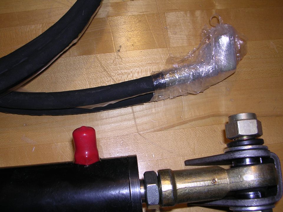 Black hose with a red cap and a metal joint with a nut, on a wooden surface
