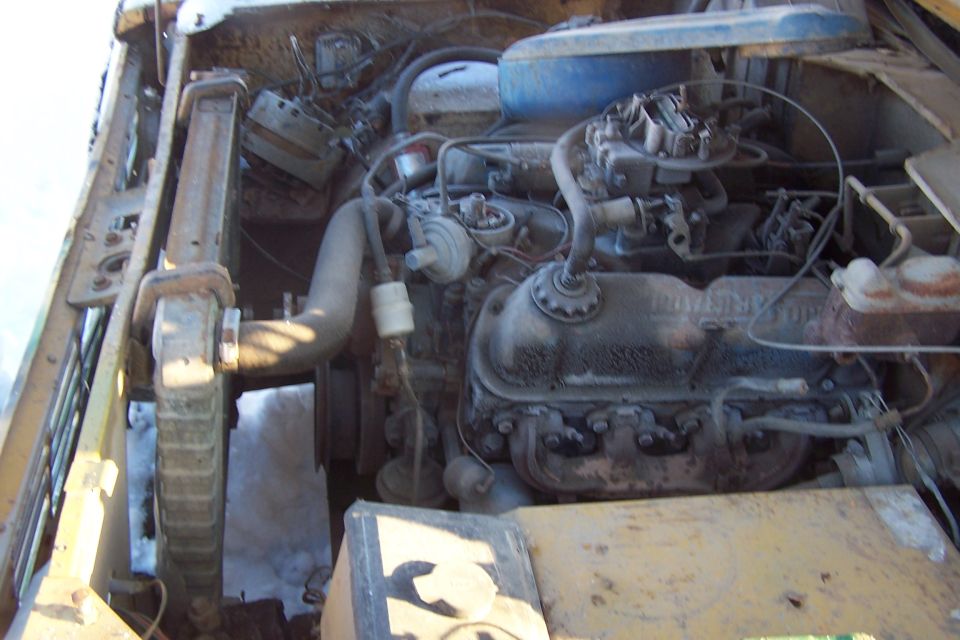 Engine bay with V8 engine, carburetor, radiator, and hoses.