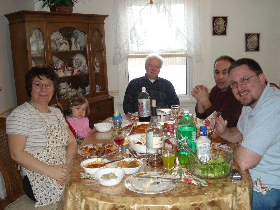 A family meal scene with people sitting at a dining table with food.