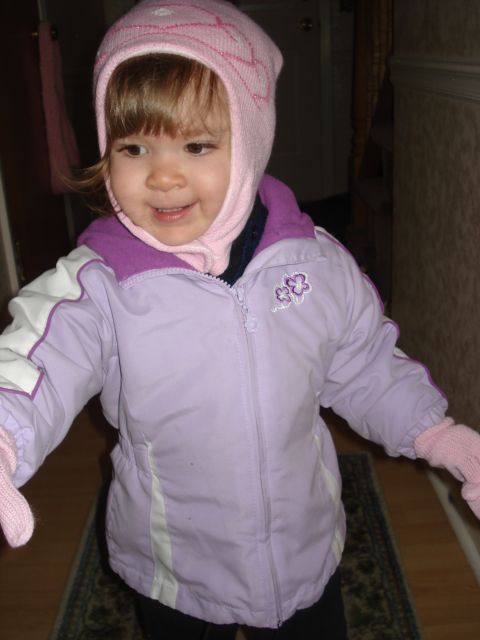 2000 Ford Crown Victoria - A young child wearing a pink hat and a purple and white jacket is looking to the side.