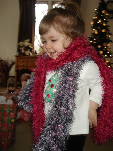 2000 Ford Crown Victoria - A young child wearing a festive scarf with a Christmas tree design on their shirt stands in front of a decorated Christmas tree.