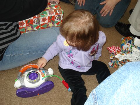 2000 Ford Crown Victoria - A young child plays with a toy karaoke machine next to wrapped Christmas presents.