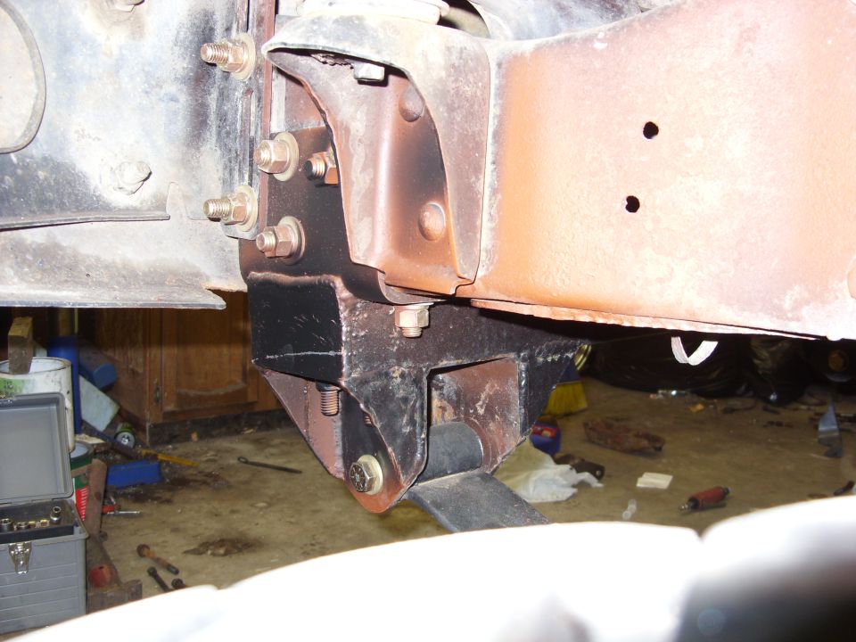 Close-up of rusty vehicle frame with black suspension bracket and bolts