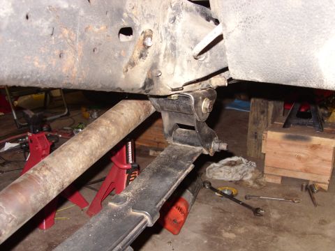 1988 Ford Bronco - Close-up view of a vehicle's leaf spring suspension system, with parts supported by jack stands.
