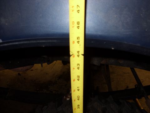 1988 Ford Bronco - A yellow tape measure is held against the fender of a blue vehicle, indicating a measurement of 44 inches.
