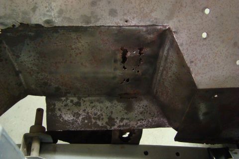 1948 Jeep Wrangler - This close-up shows significant rust and holes in a vehicle's structural metal, indicating damage or wear.