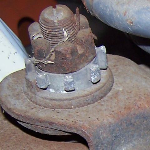 1990 Ford Bronco - A close-up view of a rusty ball joint nut secured with a cotter pin.