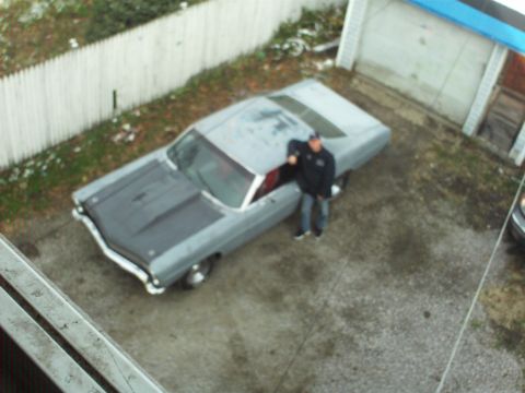 1967 Ford Galaxie - A man stands next to a classic car in a driveway, with a garage and fence in the background.