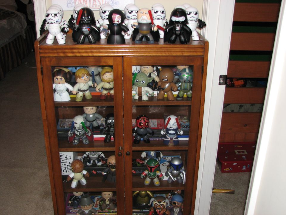Star Wars figures on shelves in a wooden cabinet