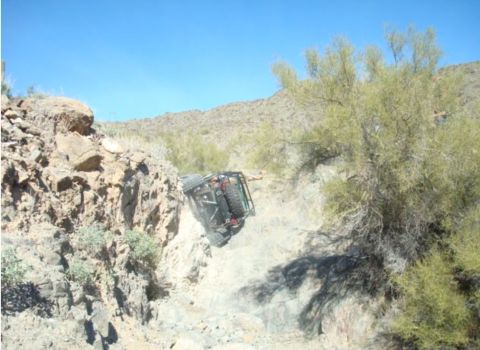 1986 Toyota Hilux - An off-road vehicle is precariously positioned on a steep, rocky desert incline.