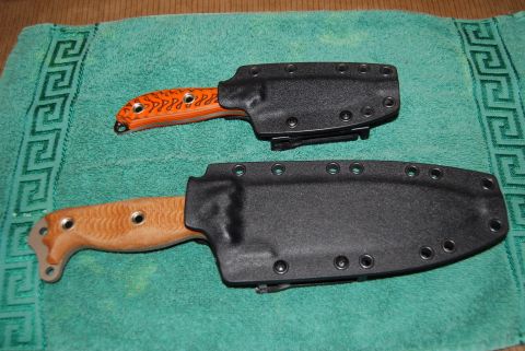1991 Ford Bronco - Two knives, one with an orange handle and the other with a wood handle, are shown in their black sheaths on a teal towel.