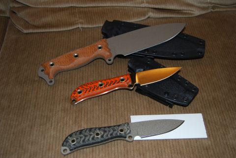1991 Ford Bronco - Three knives, each with a different handle and sheath, are displayed on a textured brown background.
