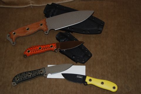 1991 Ford Bronco - A collection of knives with various handle colors and blade styles are laid out on a textured brown background.