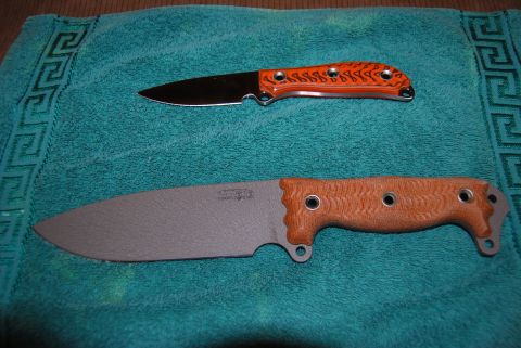1991 Ford Bronco - Two knives, one with an orange handle and flame pattern, and another with a brown textured handle, are displayed on a teal towel.
