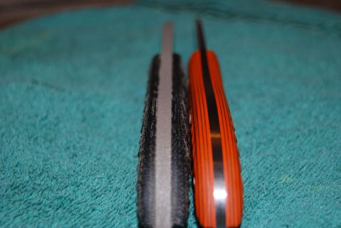 1991 Ford Bronco - Close-up side view of two knives, one with a textured black and gray handle and the other with an orange handle black stripes.