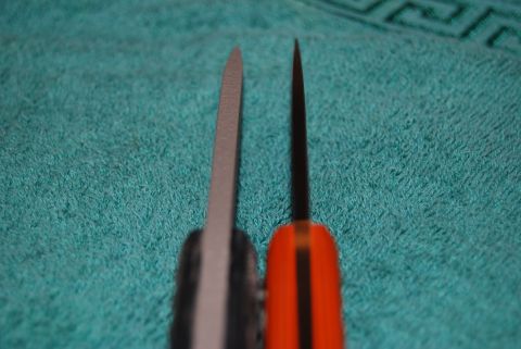 1991 Ford Bronco - Close-up view of two knife blades, one gray and one black with an orange handle.