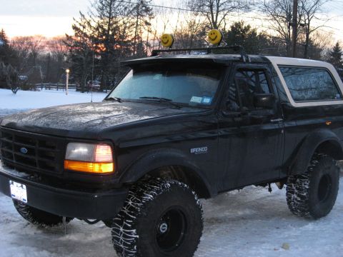 1995 Ford Bronco - A black Ford Bronco with a light bar and smiley face lights sits in the snow.