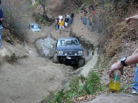 1989 Ford Bronco - A 1987 Ford Bronco navigates a challenging off-road trail while onlookers observe the action.