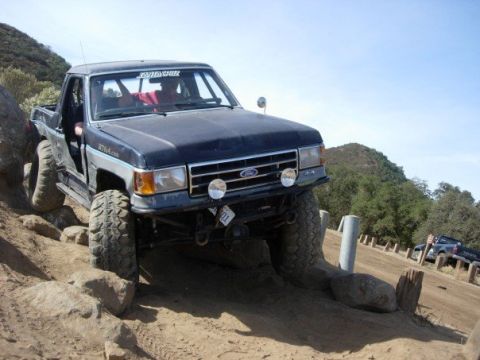 1989 Ford Bronco - This modified Ford Bronco II is tackling a challenging off-road course with large tires and lifted suspension.