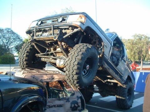 1989 Ford Bronco - This heavily modified 1989 Ford Bronco demonstrates its off-road capabilities by driving over another vehicle.