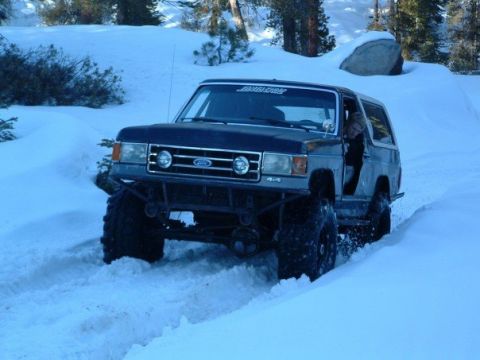 1989 Ford Bronco - This modified Ford Bronco navigates a snowy terrain, demonstrating its off-road capabilities.