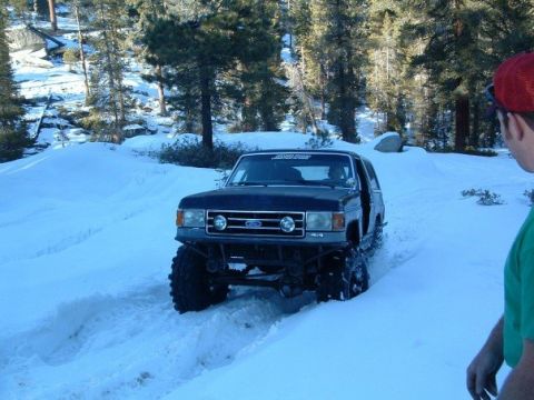 1989 Ford Bronco - A lifted black Ford Bronco navigates a snowy mountain road during a winter trip.