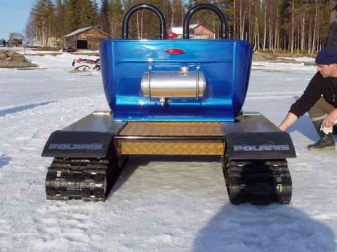 1978 Ford Bronco - A blue tracked vehicle sits on snow, with a person adjusting its fender.