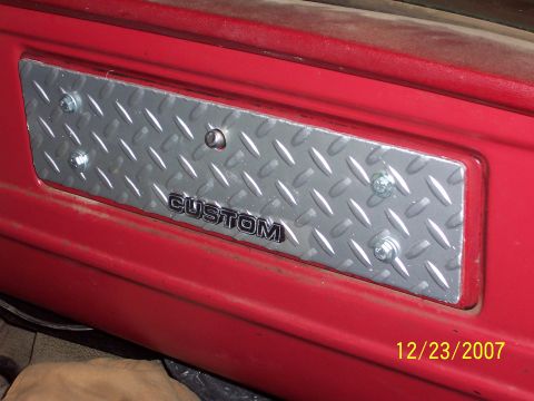 1978 Ford F-150 - Close-up of a diamond plate trim piece with the word CUSTOM affixed to a red interior panel.