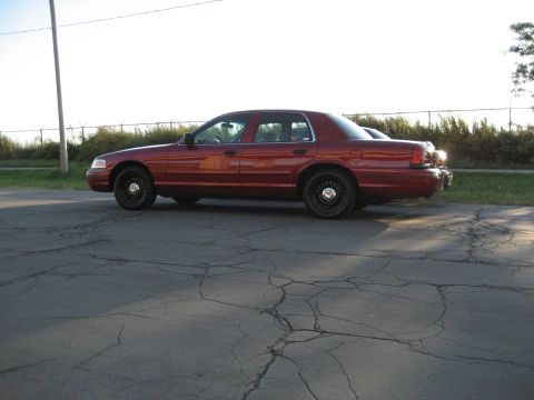2000 Ford Crown Victoria - A red 2000 Ford Crown Victoria is shown from the side, parked outdoors on a sunny day.