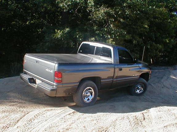 Gray Dodge Ram pickup truck with a bed cover parked on a dirt road