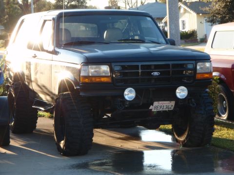 1995 Ford Bronco - Modified 1995 Ford Bronco with lifted suspension and oversized tires sits in a driveway.