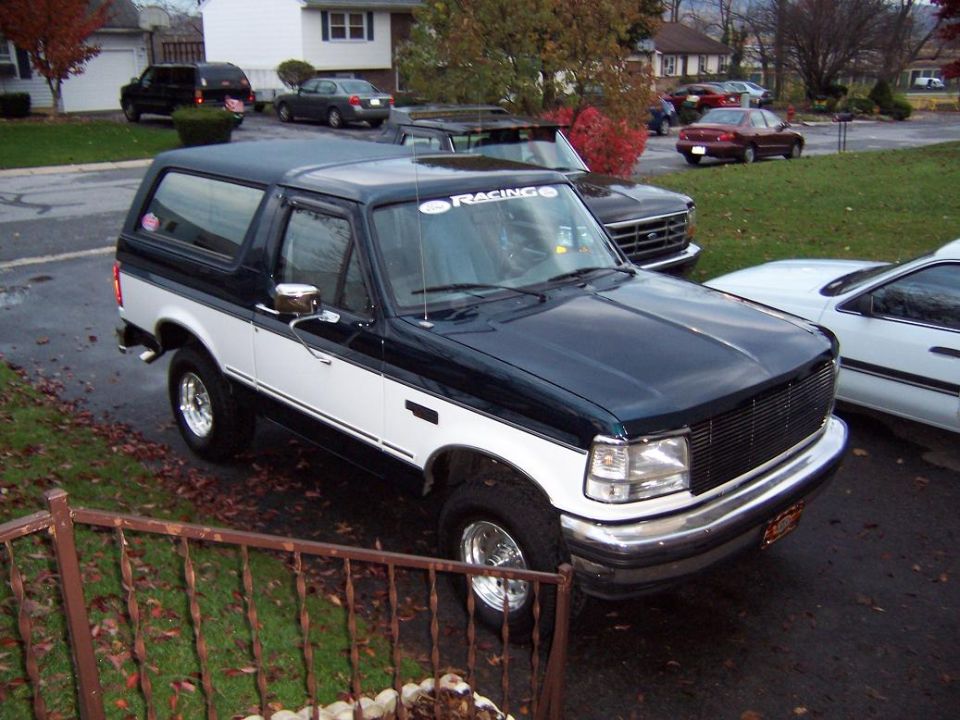1995 Ford Bronco, dark green and white, parked on a wet driveway.